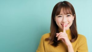 黙るよう指を口に当てる若い人物