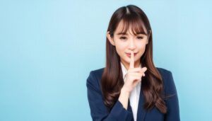 静かにと指を立てるスーツの女性