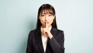 指を口元に当てて静かにと示すビジネスウーマン