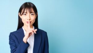 静かにと合図をするスーツ姿の若い女性