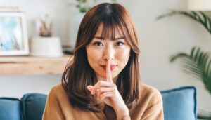 ソファで静かにのジェスチャーをする茶髪の女性