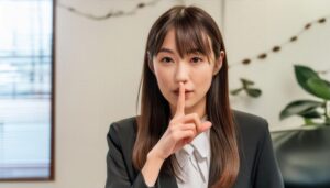 落ち着いたオフィスで静かにするジェスチャーの女性社員