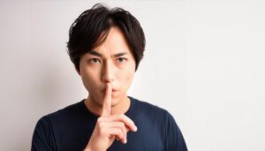 白背景で静かにするジェスチャーをする若い男性