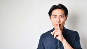 シンプルな背景で静かにするジェスチャーの男性