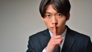 ネイビースーツで口に指を当てて黙る20代の男性