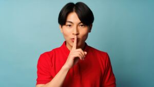 口元に人差し指を当てて静かにするポーズの若者