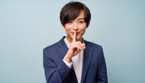 笑顔で口元に指を当て静かにのジェスチャーをする若者
