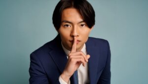 口に人差し指を当てて静かにするサインを示す若者