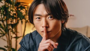 人差し指を口元にあて静かにするようジェスチャーする男性