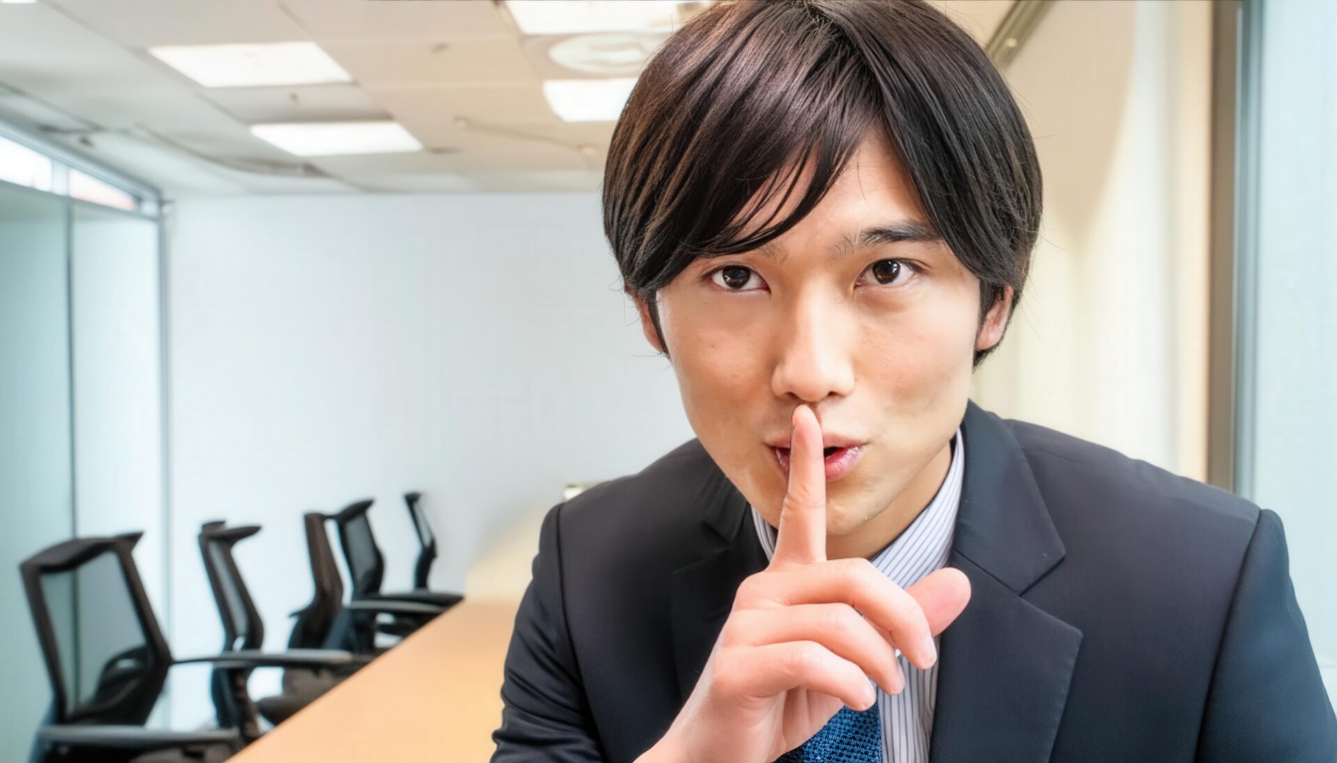 会議室で口元に指をあてるビジネスマン