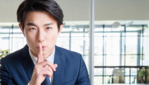 オフィスで静かにのジェスチャーをする若い会社員