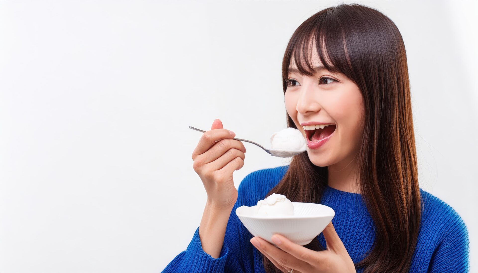 バニラアイスを食べる女性（青セーター）