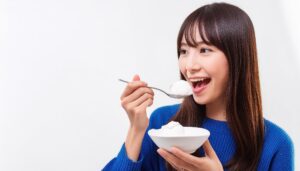 バニラアイスを食べる女性（青セーター）