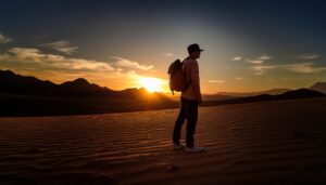夕焼けの砂漠に立つバックパッカー