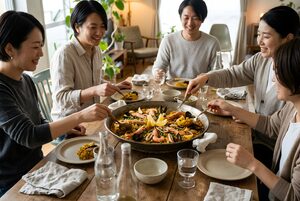 鍋を囲んでパエリアを取り分ける友人たち
