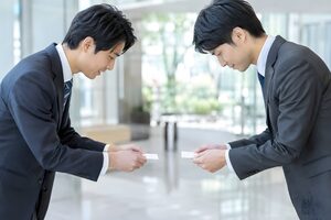 オフィスのロビーで両手で名刺交換をする2人の男性