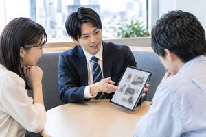 小さな商談ブースでタブレットのカタログを見せる20代の営業担当