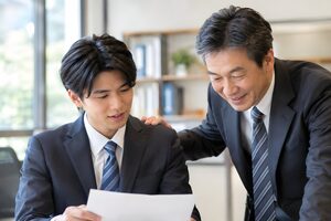 若手の肩に手を添えて励ます50代の上司