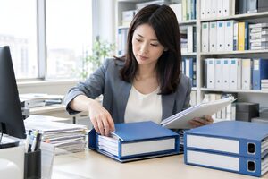 書類をバインダーに整理する30代の事務職女性