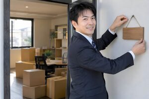 新しいオフィスの入口に社名のプレートを取り付ける40代男性