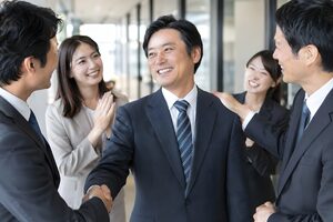 昇進した40代男性を祝って握手する同僚たち