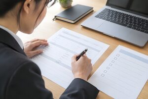 目標シートを見ながら自己評価表に記入する社員の手元