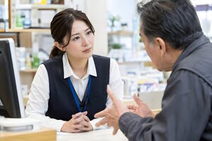 カウンターで怒った客の話を落ち着いて聞く30代の女性担当者