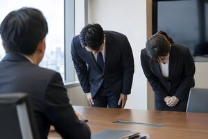 取引先の前でそろって頭を下げる2人の担当者