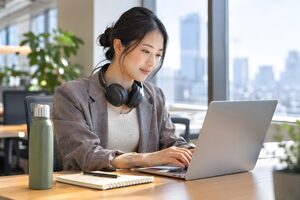 窓際のフリーアドレス席でノートパソコンに向かう30代女性