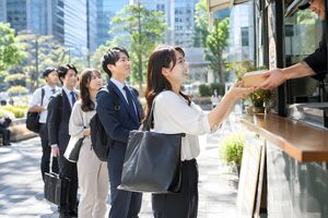 ランチタイムのオフィス街でキッチンカーに並ぶ社員たち