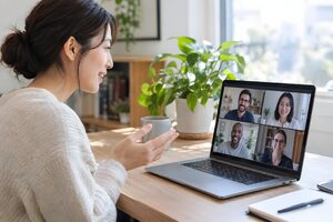 自宅のノートパソコンで4人の同僚とオンライン会議をする30代女性