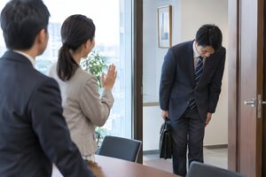訪問を終えて客先の出口でお辞儀をする20代の営業マン