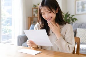 自宅で内定通知書を読んで安堵の笑顔を見せる20代女性
