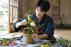 竹かごの花器に季節の花を生ける20代男性