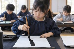 書道教室で半紙に向かう小学生の女の子