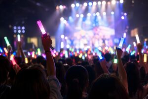暗いライブ会場でペンライトを振るファンたち