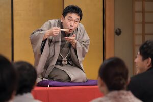 扇子を箸に見立てて蕎麦を食べる仕草をする落語家