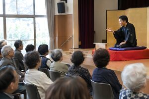 公民館のホールで落語を楽しむ高齢の観客