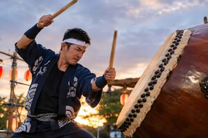 祭りの舞台で大太鼓を打つ法被姿の30代男性