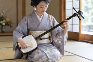 畳の部屋で三味線を弾く着物姿の40代女性