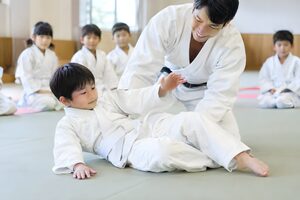 子ども柔道教室で受け身を教わる8歳くらいの男の子