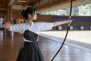 弓道場で弓を引き絞る20代の女性射手