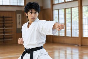 道場で突きを繰り出す黒帯の20代男性
