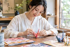 工房で和紙を折って鶴を作る30代女性