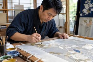 枠に張った絹に糊で模様を描く友禅の職人