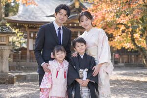 神社で記念写真に収まる七五三の家族4人