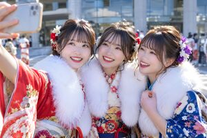 会館の前で振袖姿で自撮りをする3人の新成人