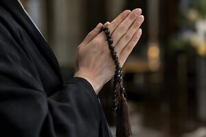 喪服姿で数珠を手に合掌する手元