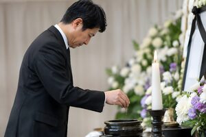 葬儀で焼香をする喪服の40代男性