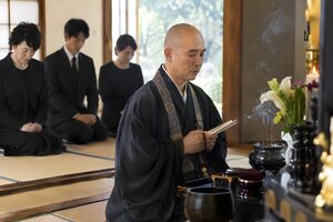 法事で読経する僧侶と正座で聞く家族